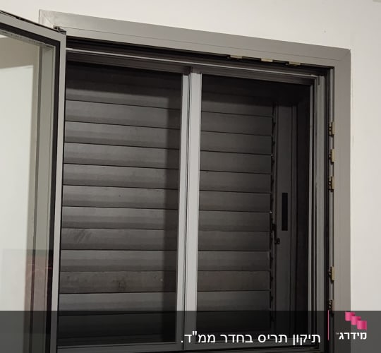 תריסים אפורים סגורים במסגרת חלון לבנה